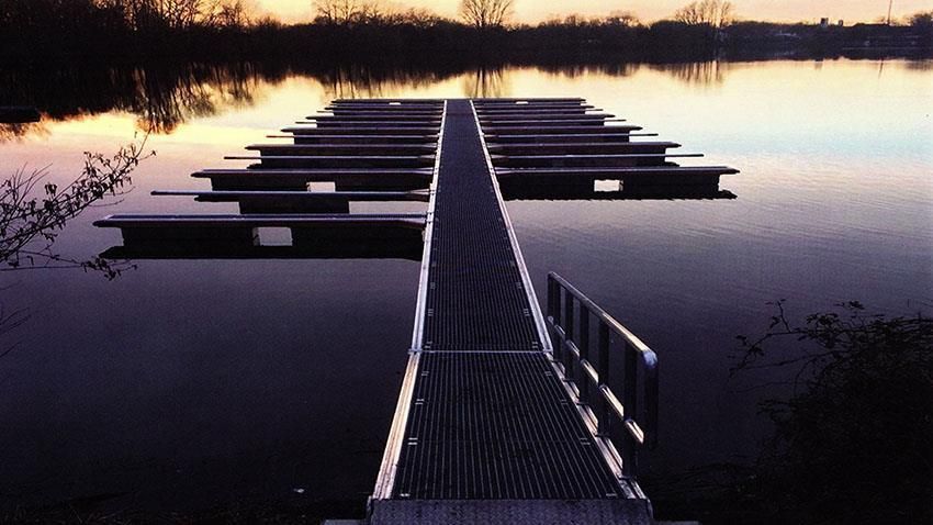 Ein Steg, der zu einem See führt, mit einem Sonnenuntergang im Hintergrund