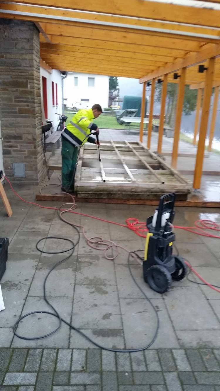 Ein Mann arbeitet unter einem Baldachin an einer Holzkonstruktion.