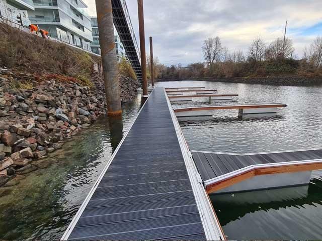 Ein Dock, das zu einem Gewässer führt, mit einer Brücke im Hintergrund.