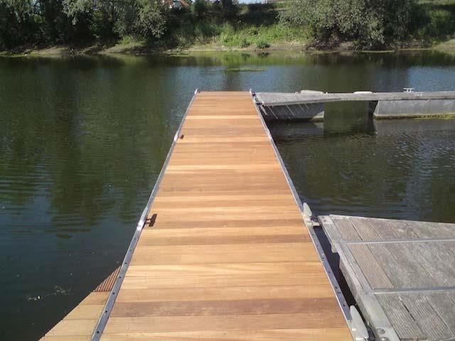 Ein Holzsteg liegt neben einem Gewässer