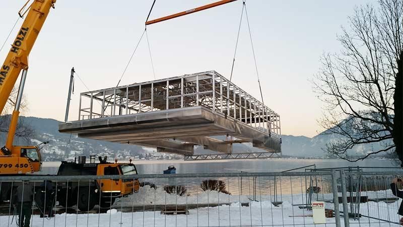 Ein Kran hebt eine große Metallkonstruktion über ein Gewässer