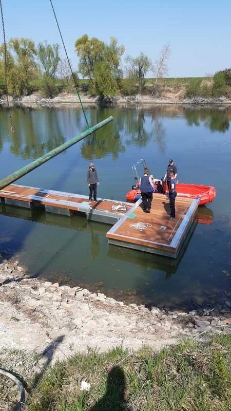 Eine Gruppe von Menschen steht auf einem Steg mitten auf einem See.