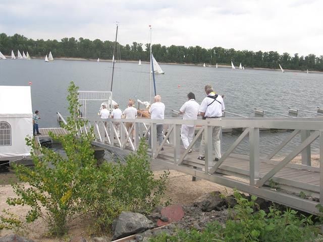 Eine Gruppe von Menschen steht auf einem Dock und blickt auf ein Gewässer