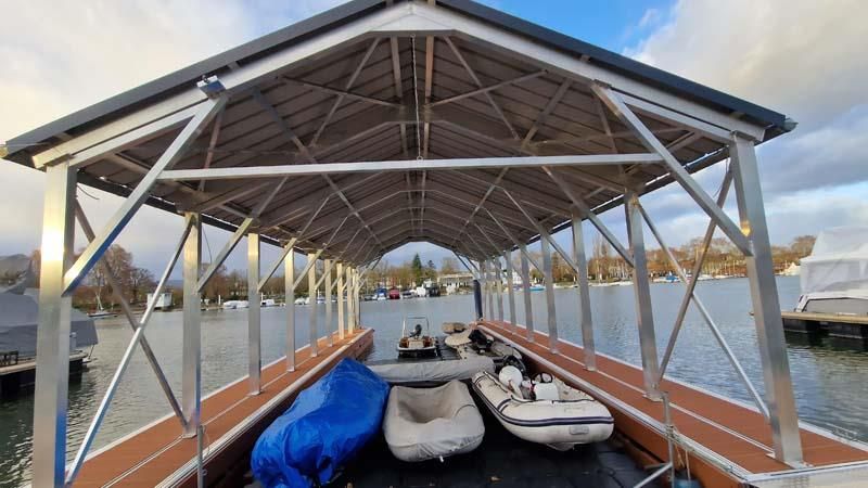 Ein Boot liegt unter einem überdachten Steg auf einem See.