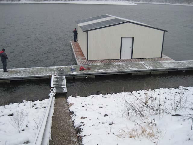 Zwei Männer stehen auf einem Dock neben einem Gebäude im Wasser