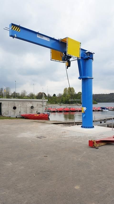 Ein blau-gelber Kran steht auf einem Parkplatz in der Nähe eines Gewässers