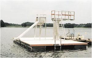 Eine schwimmende Plattform mit Rutsche und Treppe im Wasser.
