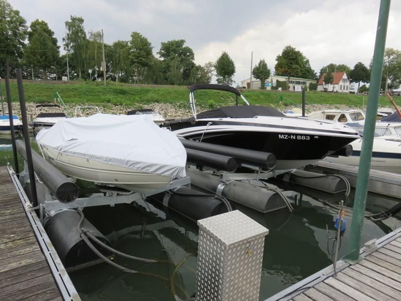 An einem Dock liegt ein Boot mit einer weißen Abdeckung.