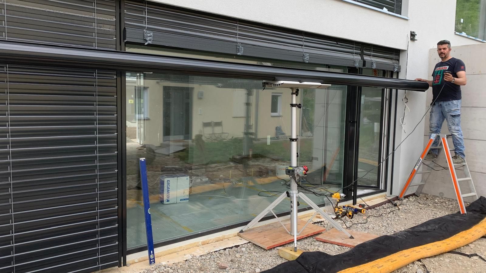 Ein Mann montiert Jalousien an einem Fenster.