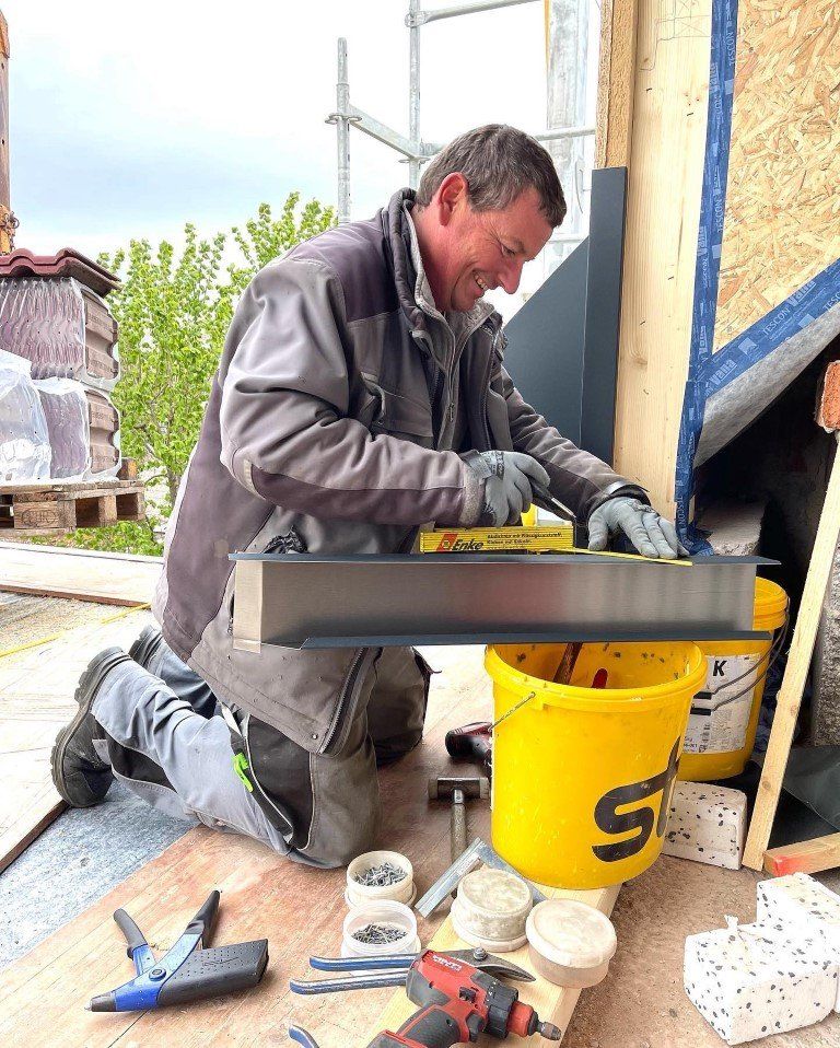 Mitarbeiter von Blechnerei und Haustechnik Rommler mit Bohrer in der Hand auf einem Dach
