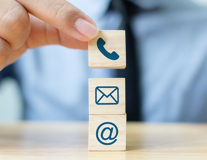 Eine Person stapelt Holzklötze mit Kontaktsymbolen darauf.