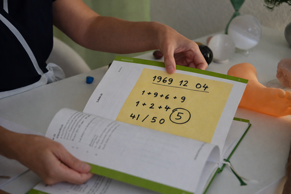 Hände, die während einer Massage heisse Steine ​​auf einen Fuss legen.