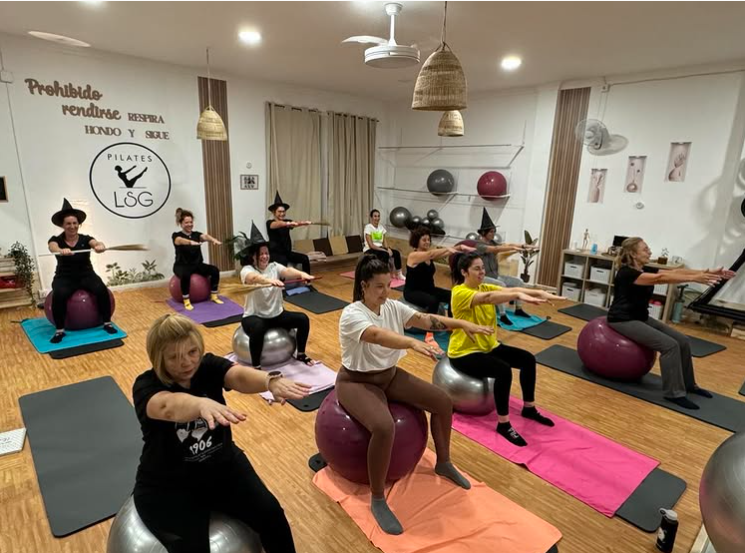 Un grupo de mujeres está haciendo yoga sobre pelotas de ejercicio en un gimnasio.