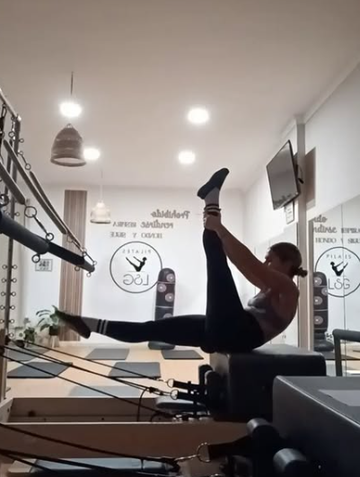 Una mujer está haciendo un levantamiento de piernas en una máquina de pilates.