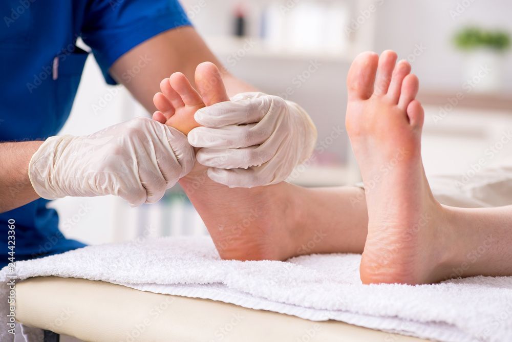 Einem Kunden wird in einem Spa eine Fussmassage mit weissen Handtüchern gegeben.