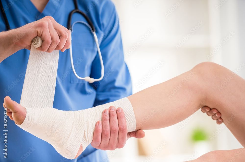 Medizinische Fachkraft verbindet das Bein eines Patienten in einer Klinik