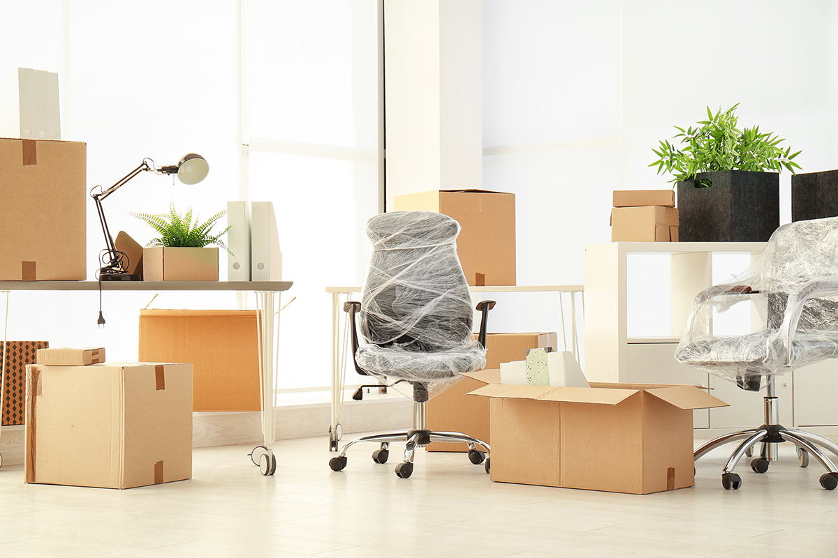 Cartons et chaises emballées à côté de bureaux