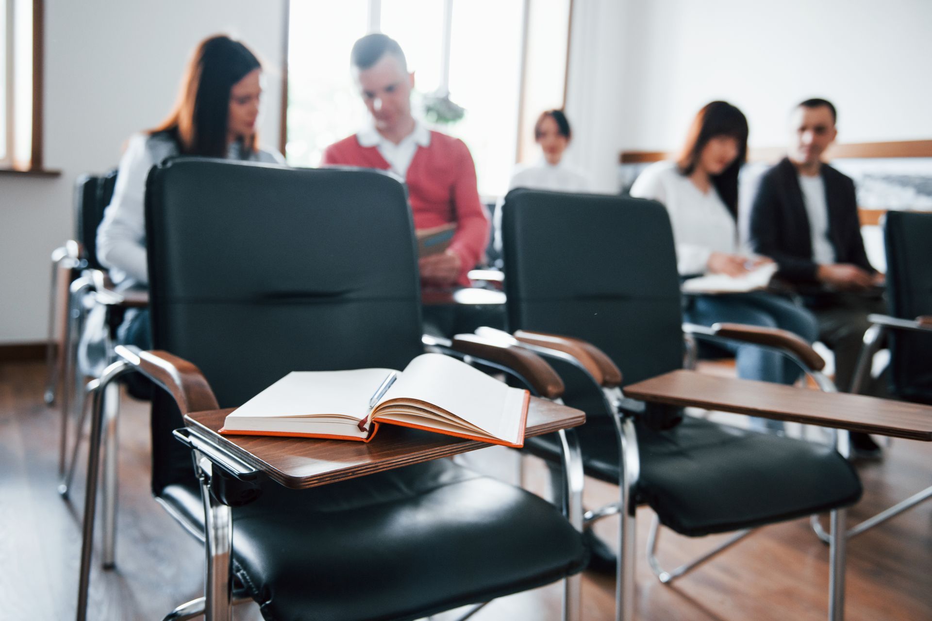 Un grupo de personas están sentadas en sillas en un aula.