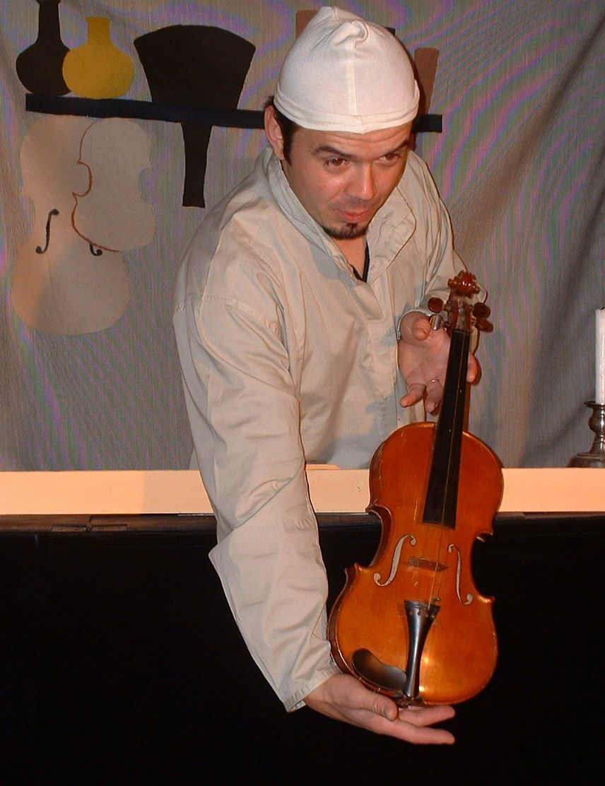 Une personne vêtue de blanc et coiffée d'une casquette, tenant un violon