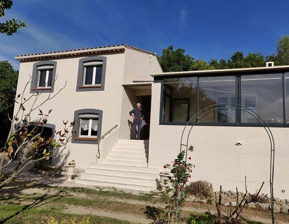 Façade d'une maison rénovée avec un monsieur devant la porte d'entrée