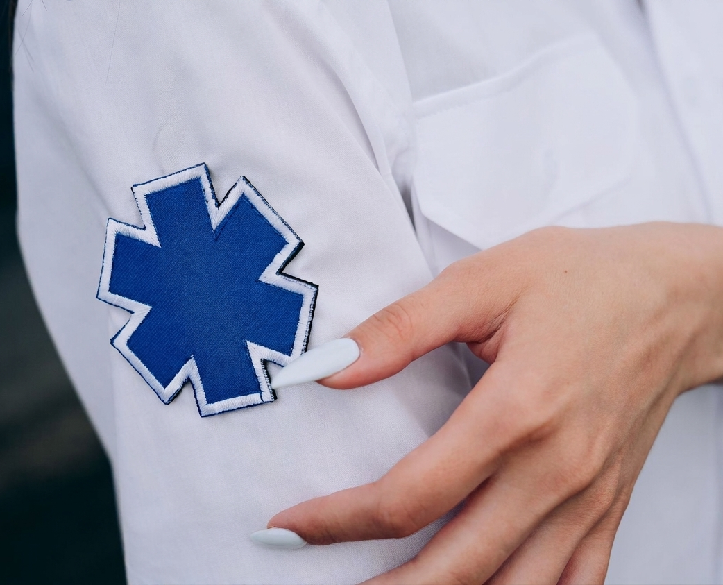 Gros plan sur une main tenant un écusson bleu d'alerte médicale sur une chemise blanche