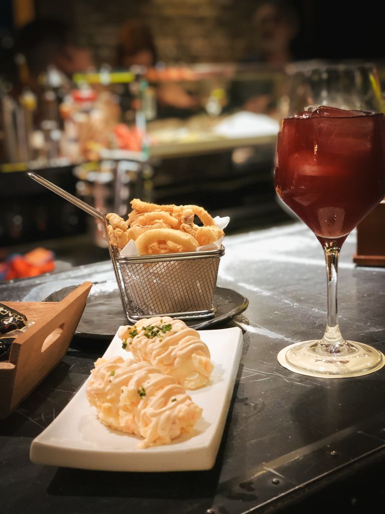 Calamares fritos y aperitivo en la barra con una copa de vino tinto.
