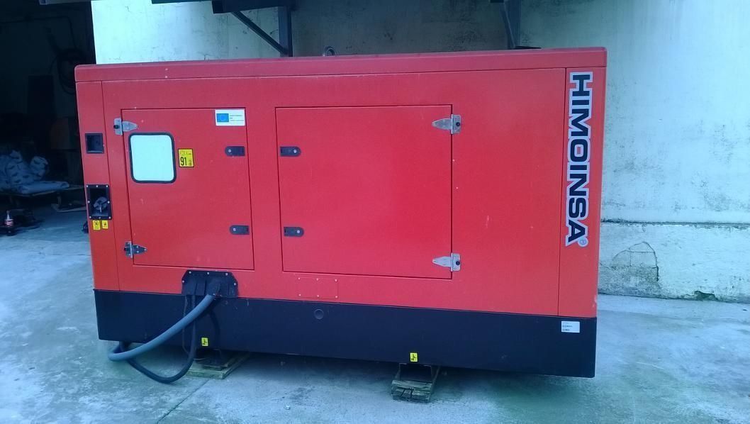 Un generador industrial rojo sobre un suelo de hormigón junto a una pared, con base negra y logotipo vertical.