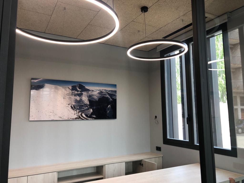 Sala de estar moderna con iluminación anular, ventanal grande, obras de arte en las paredes y bancos empotrados.