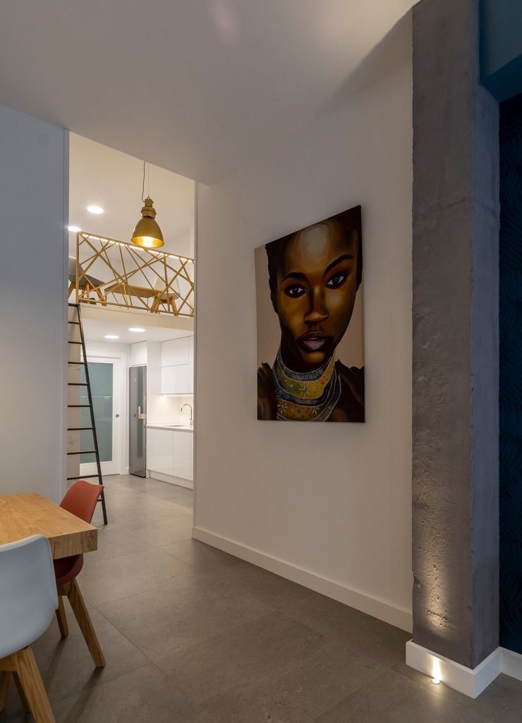 Pasillo moderno con un retrato en la pared, lámparas colgantes y una vista parcial de la cocina al fondo.