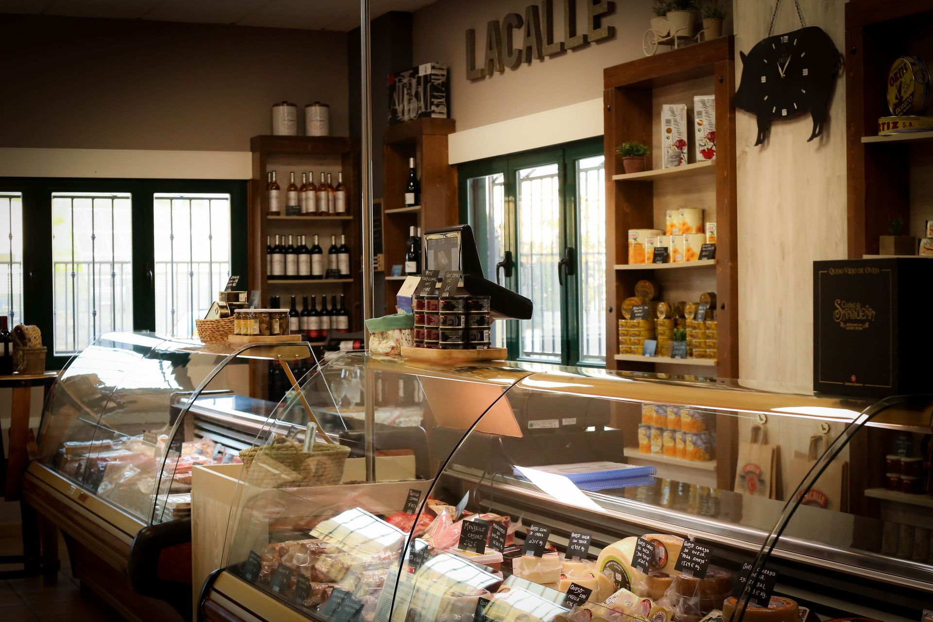Interior de una panadería con vitrinas de cristal, estantes con productos envasados e iluminación cálida.