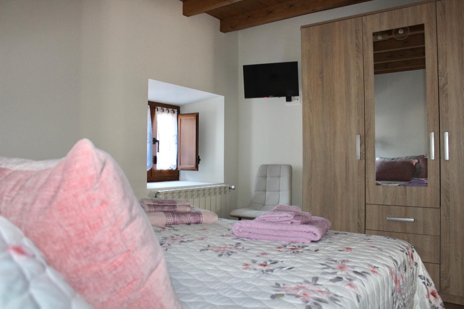 Acogedor salón con sofá seccional beige, mesa de centro de madera, vigas a la vista y grandes ventanales