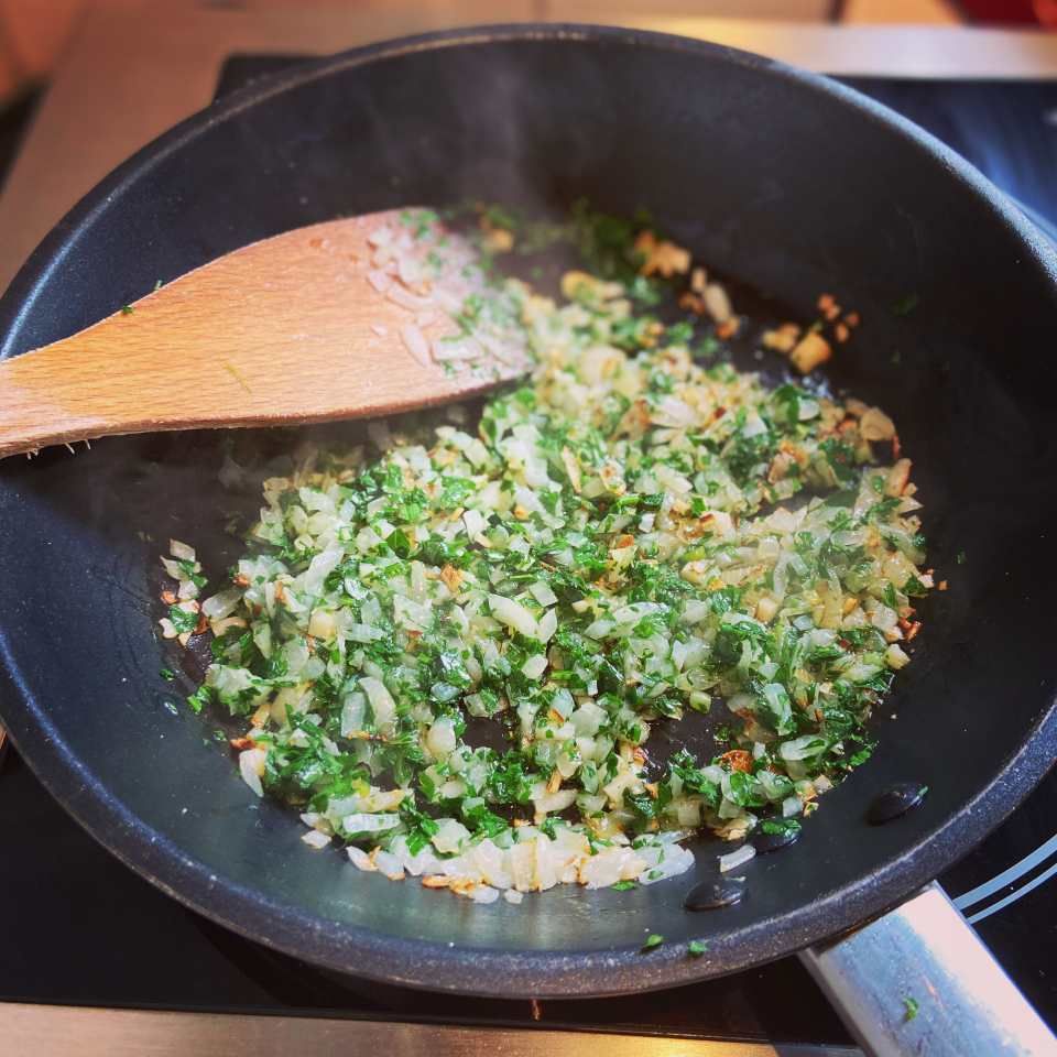 Vogelperspektive auf eine Pfanne, in der ein Gericht zubereitet wird