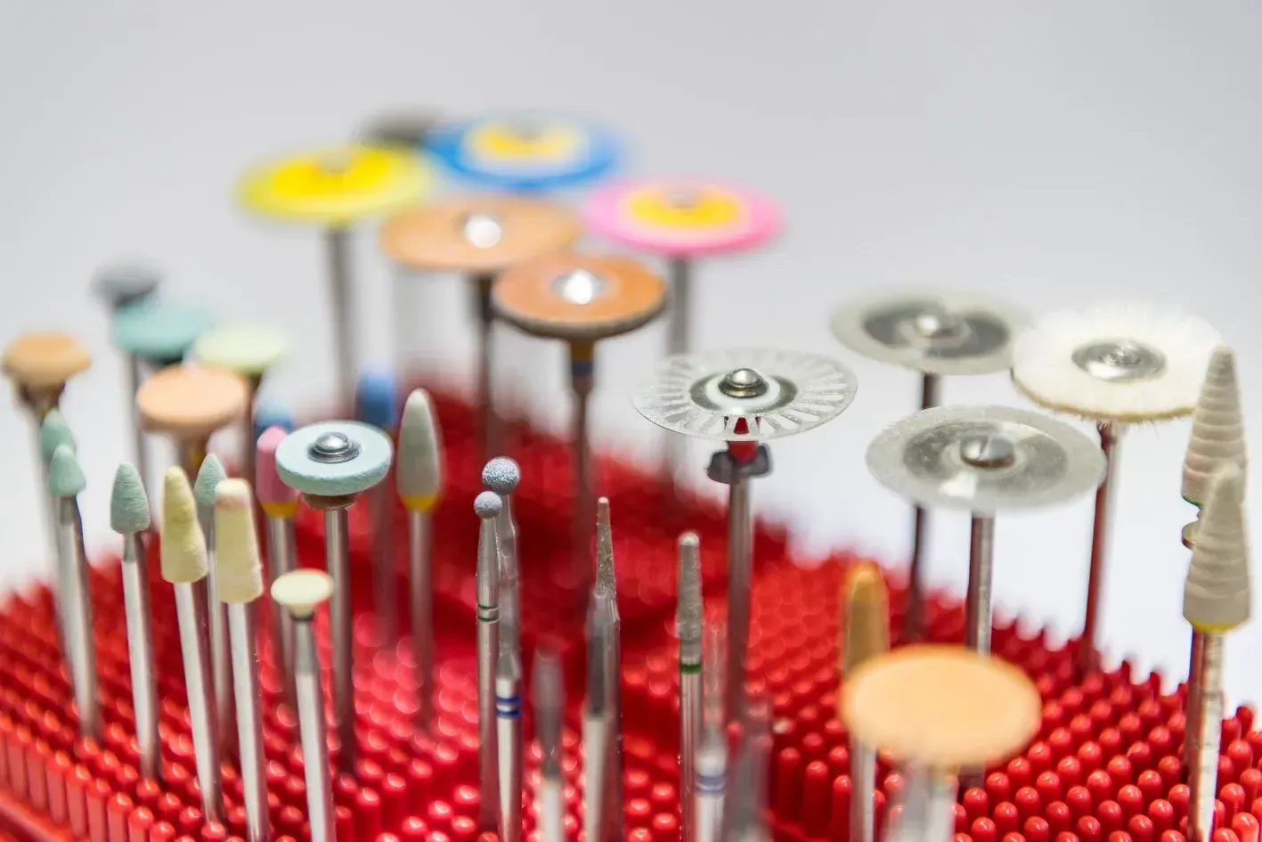 Eine Reihe von verschiedenen Arten von Zahnbohrern auf einer roten Matte, Dentaltechnik Claudia Meier
