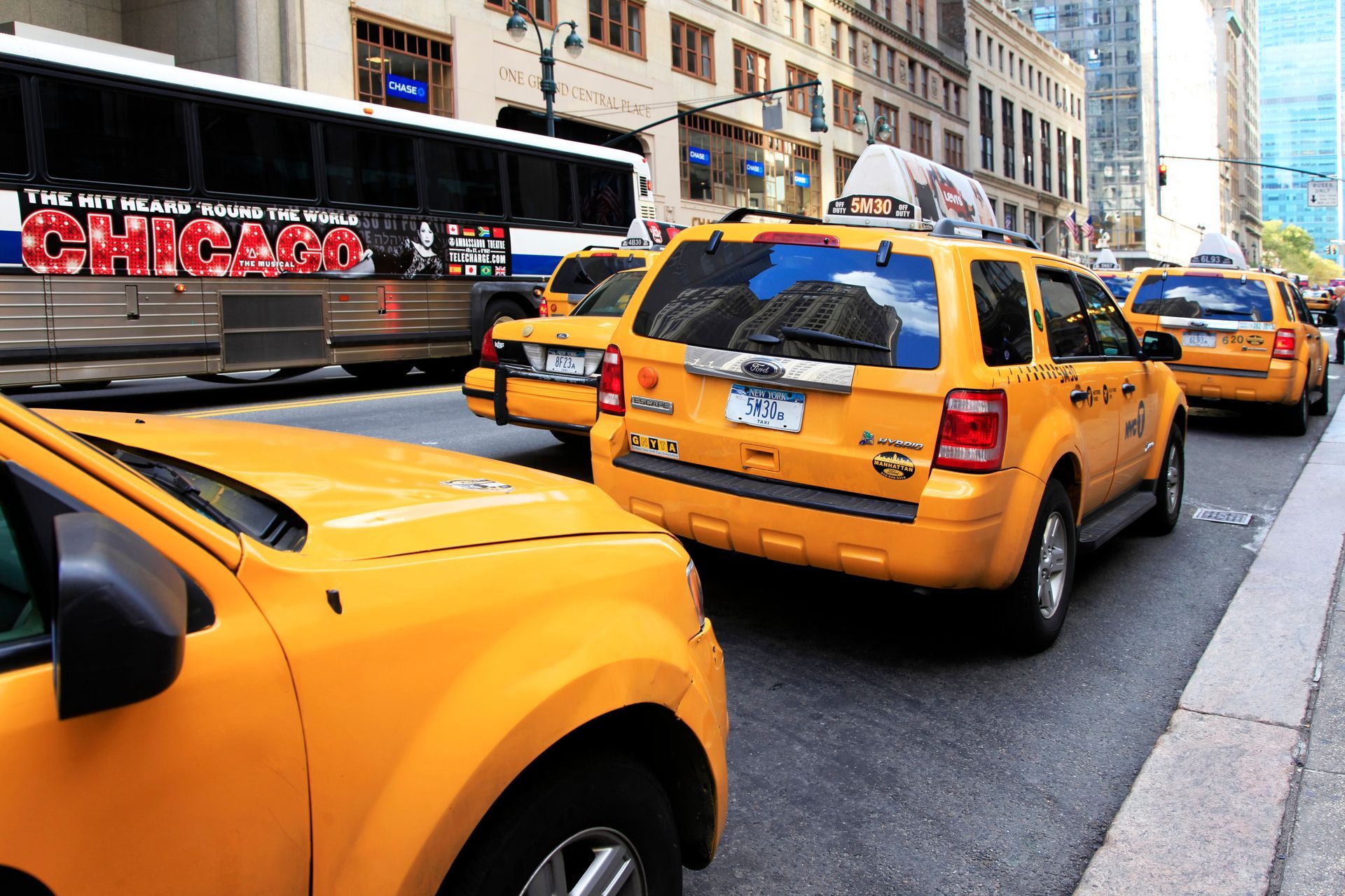 Taxis amarillos en una calle de la ciudad, con un autobús al fondo. Edificios a lo largo de la calle.