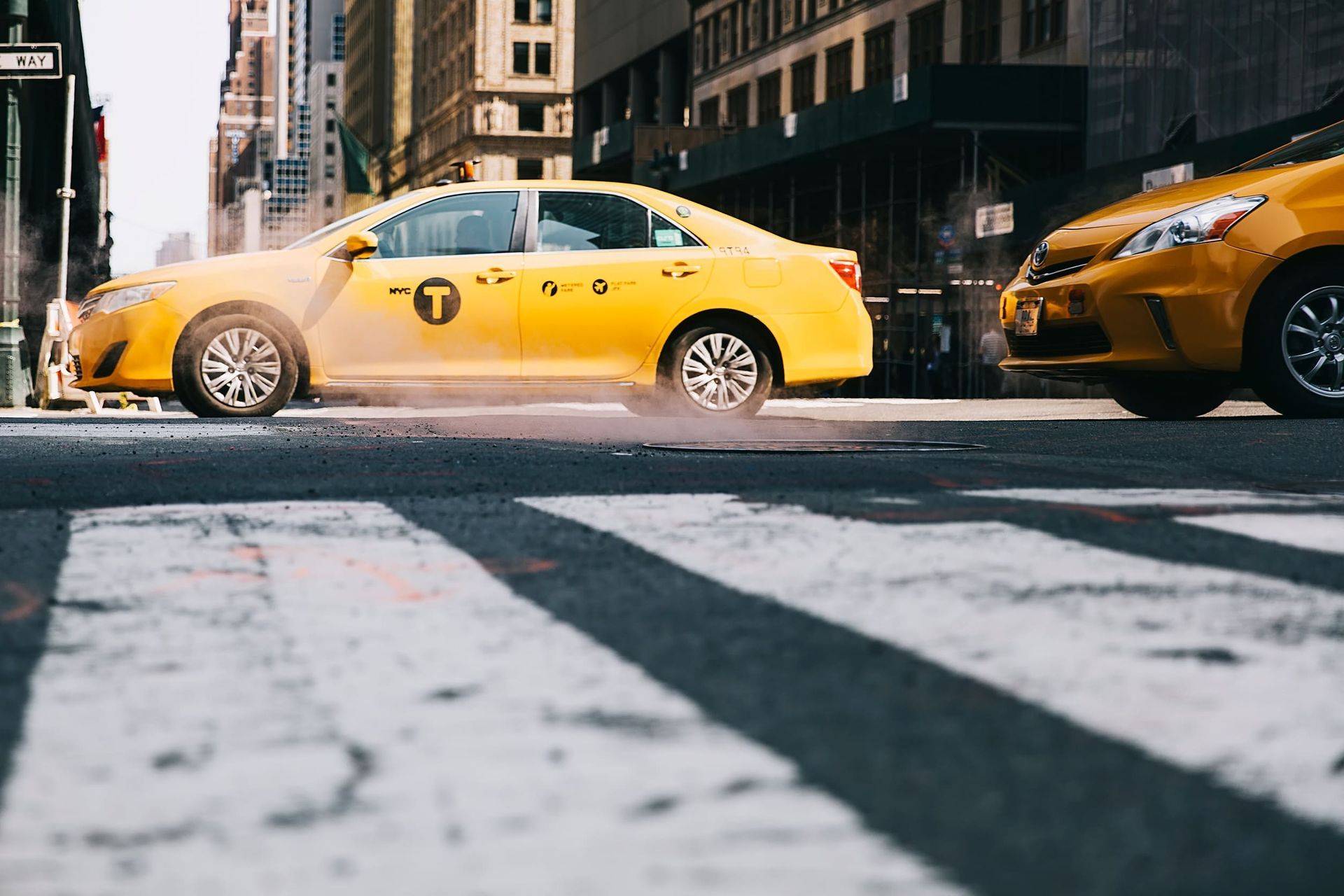 Taxis amarillos en una calle de la ciudad, uno de ellos cruzando un cruce de peatones.