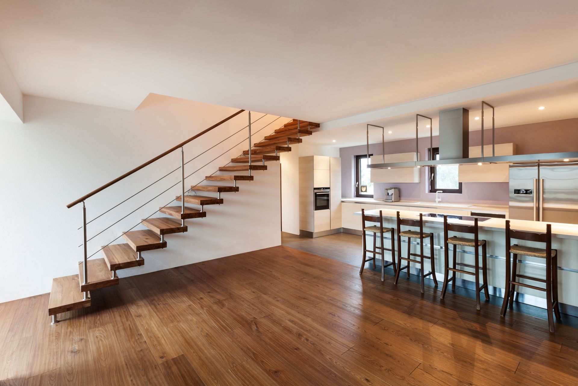 Cuisine américaine moderne avec escalier en bois et parquet.