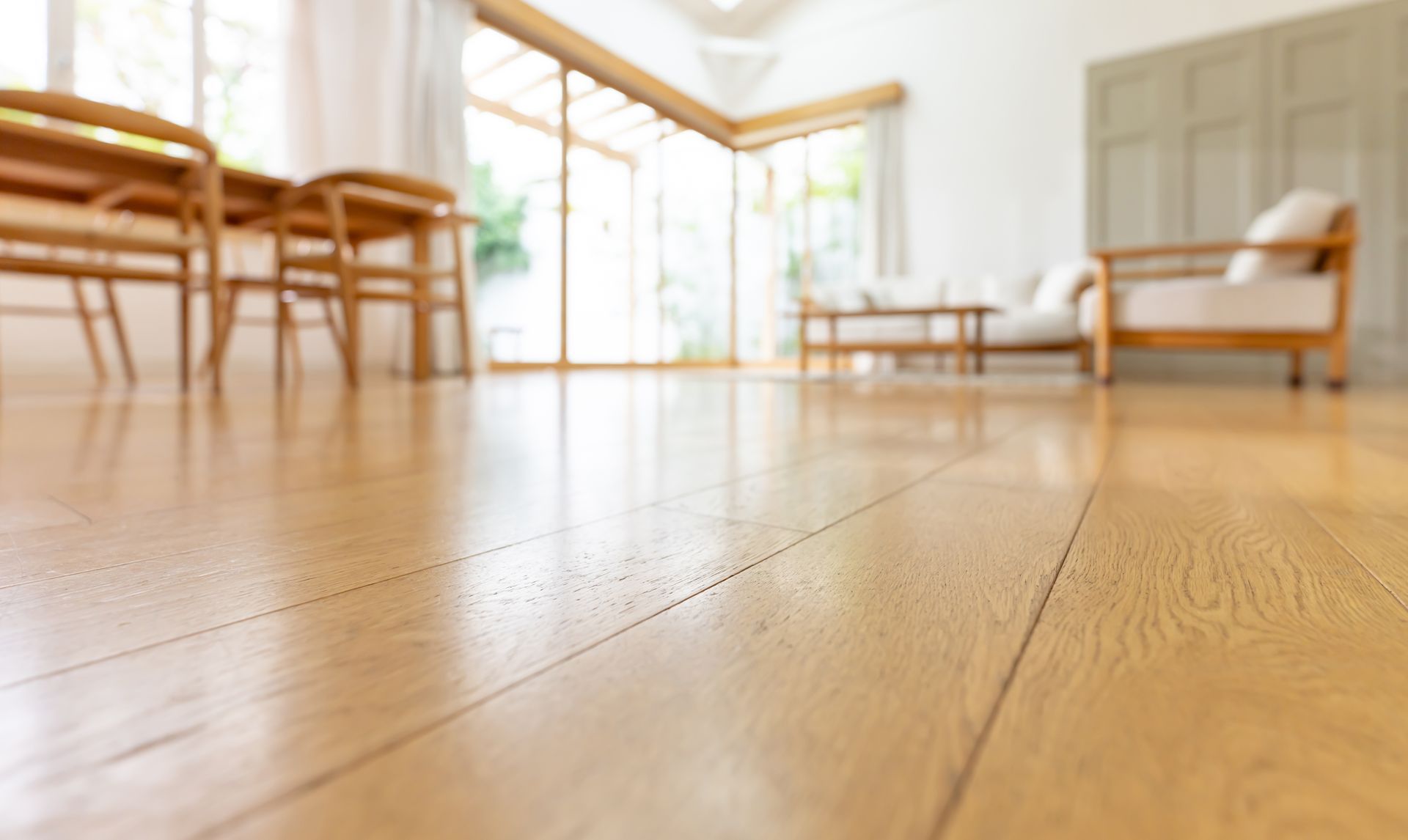 Vue en contre-plongée d'un parquet clair dans un espace de vie lumineux et flou, meublé.