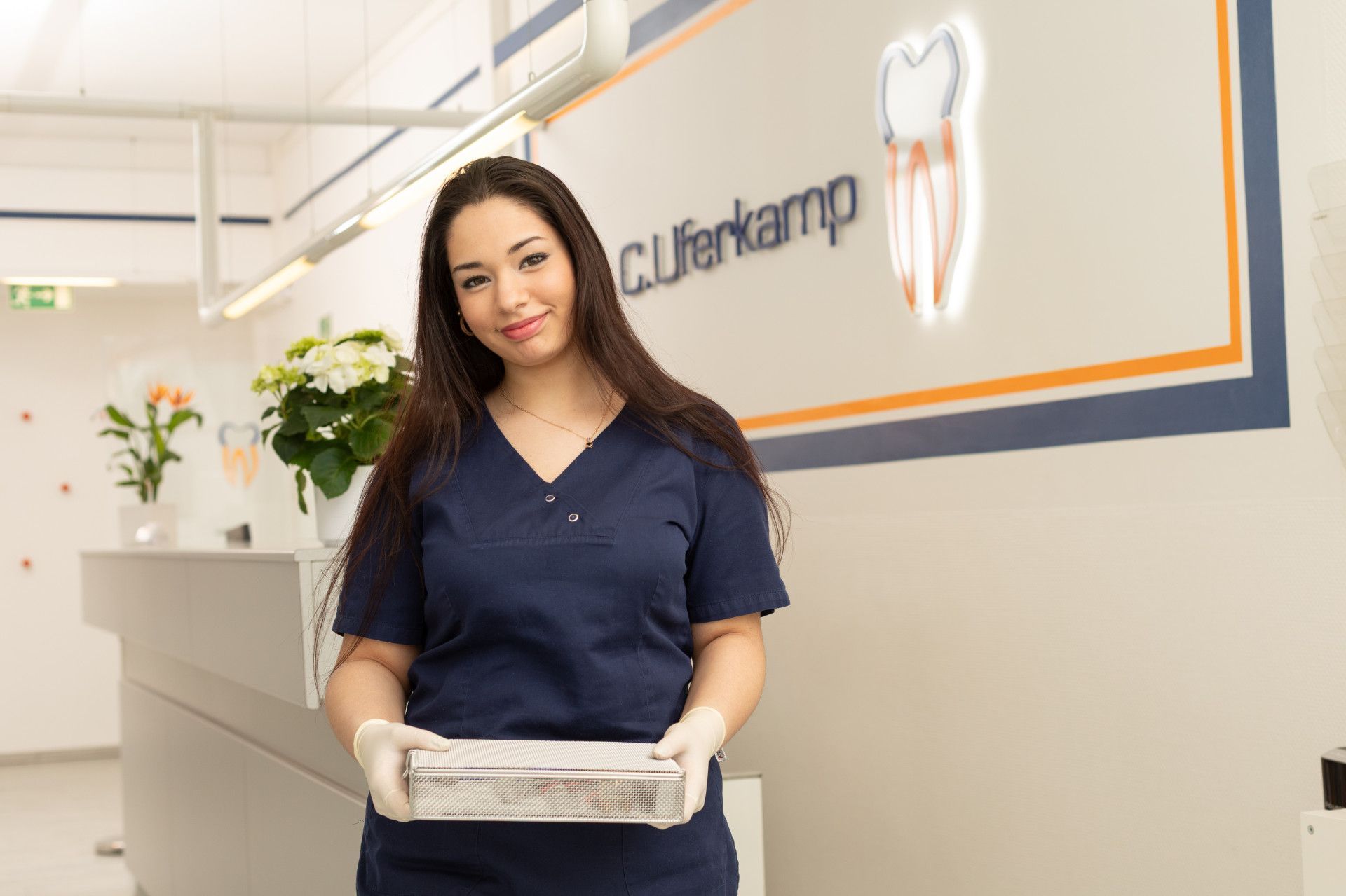 Eine Frau in einer Zahnarztpraxis hält eine Schachtel Taschentücher in der Hand.