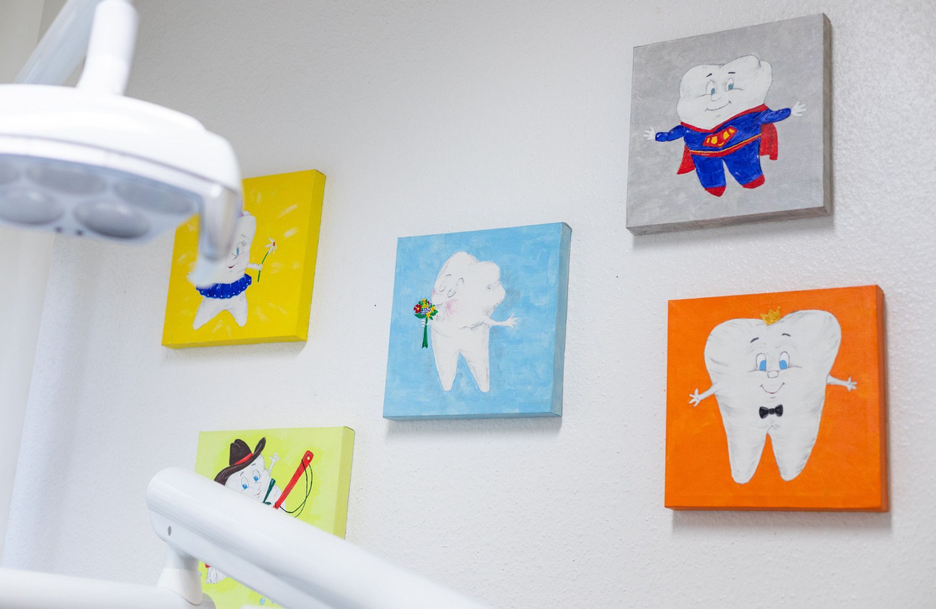 Eine Zahnarztpraxis mit Zahngemälden an der Wand.