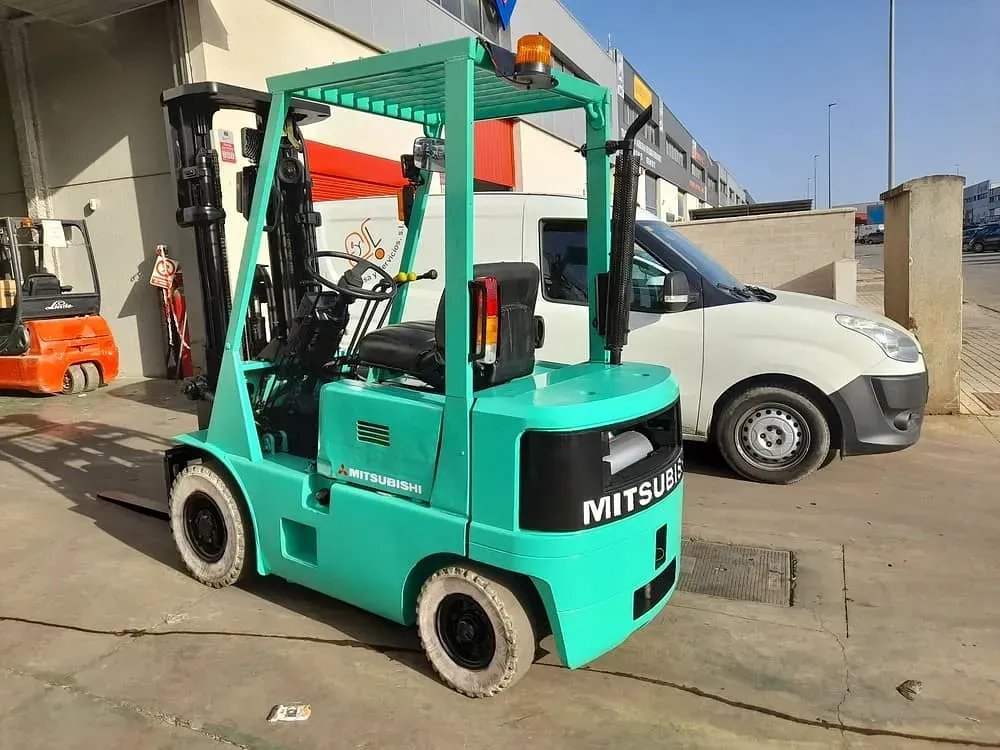 Una carretilla elevadora verde está estacionada frente a un edificio.