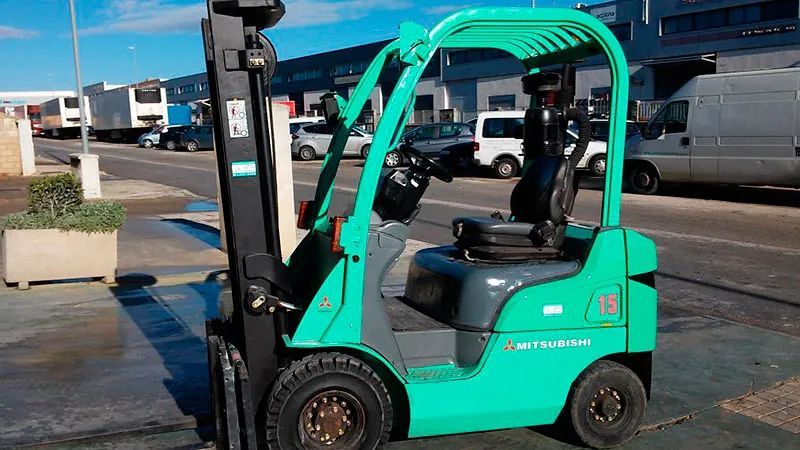 Una carretilla elevadora verde está estacionada en un estacionamiento.