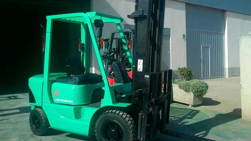Una carretilla elevadora verde está estacionada frente a un edificio.