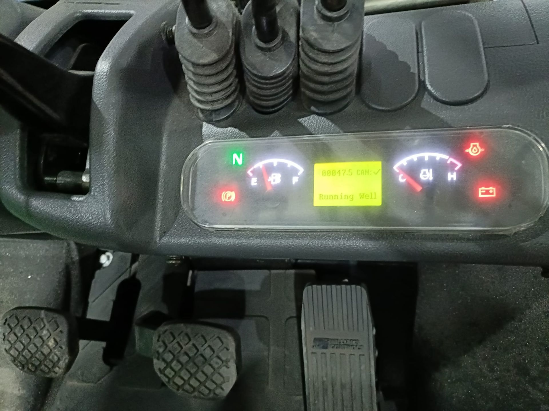 Primer plano del salpicadero de un vehículo con luces de advertencia iluminadas e indicadores cerca de los pedales.
