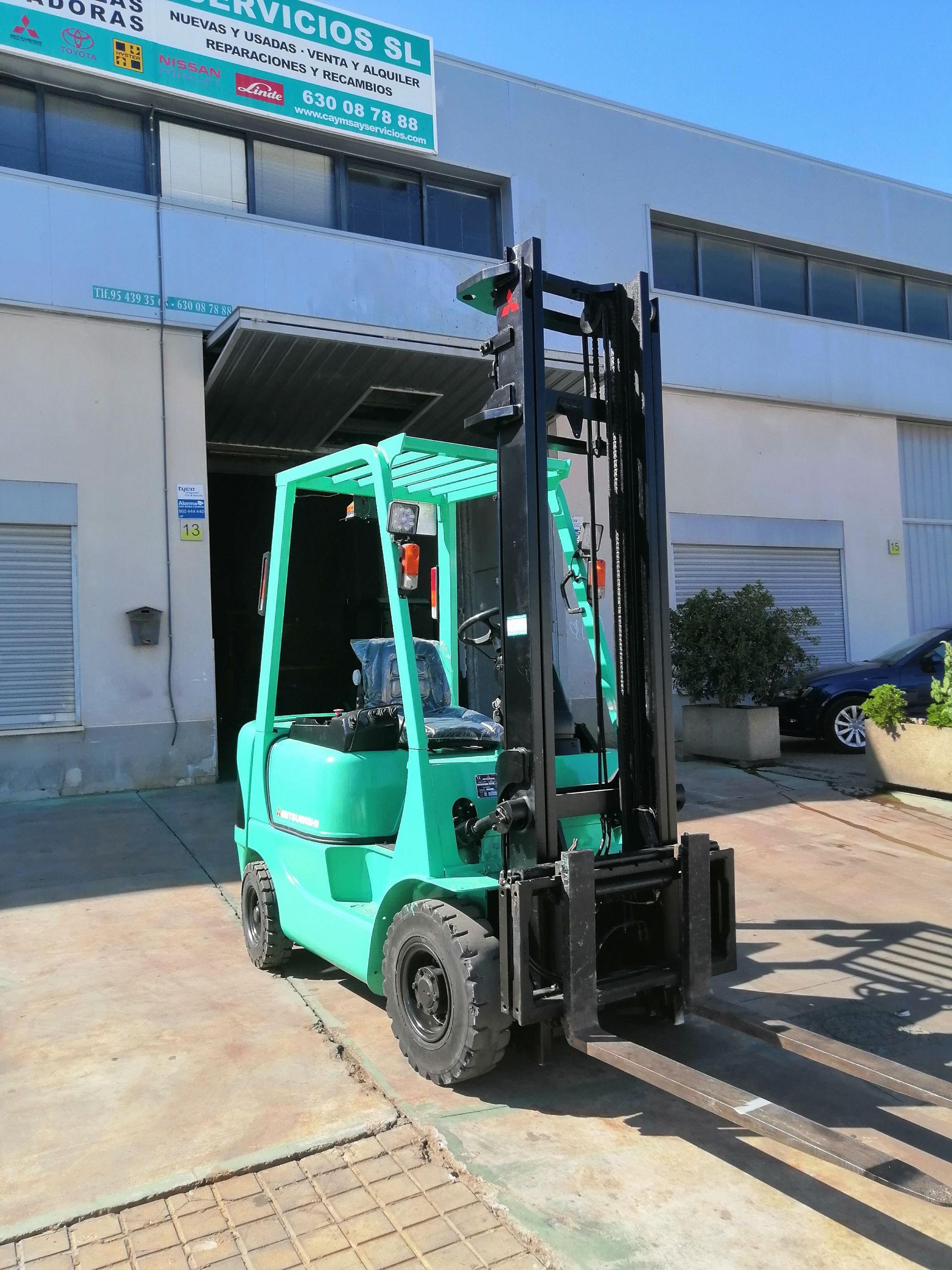 Una carretilla elevadora verde está estacionada en un estacionamiento.