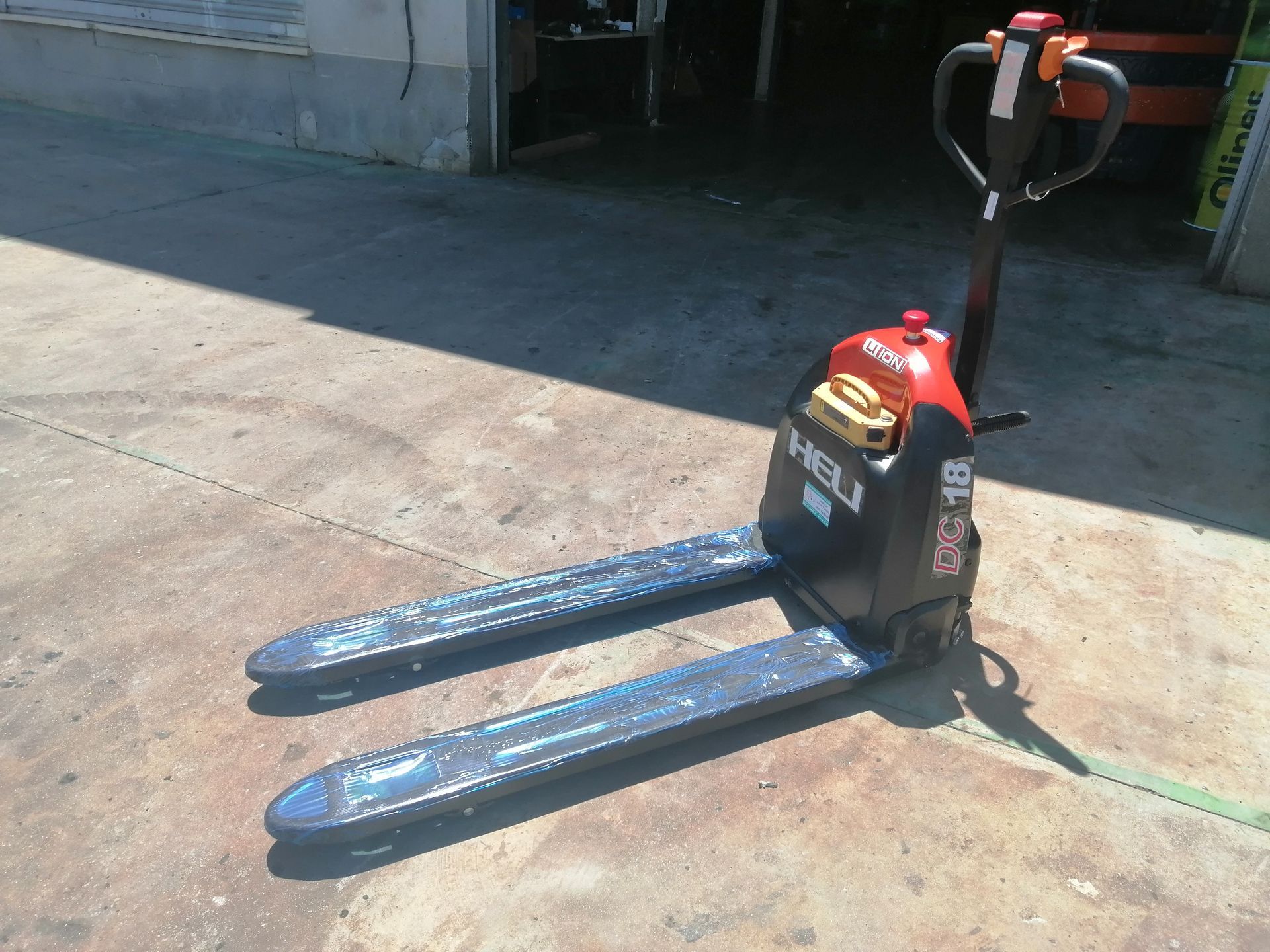 Una transpaleta está parada en el suelo en un estacionamiento.