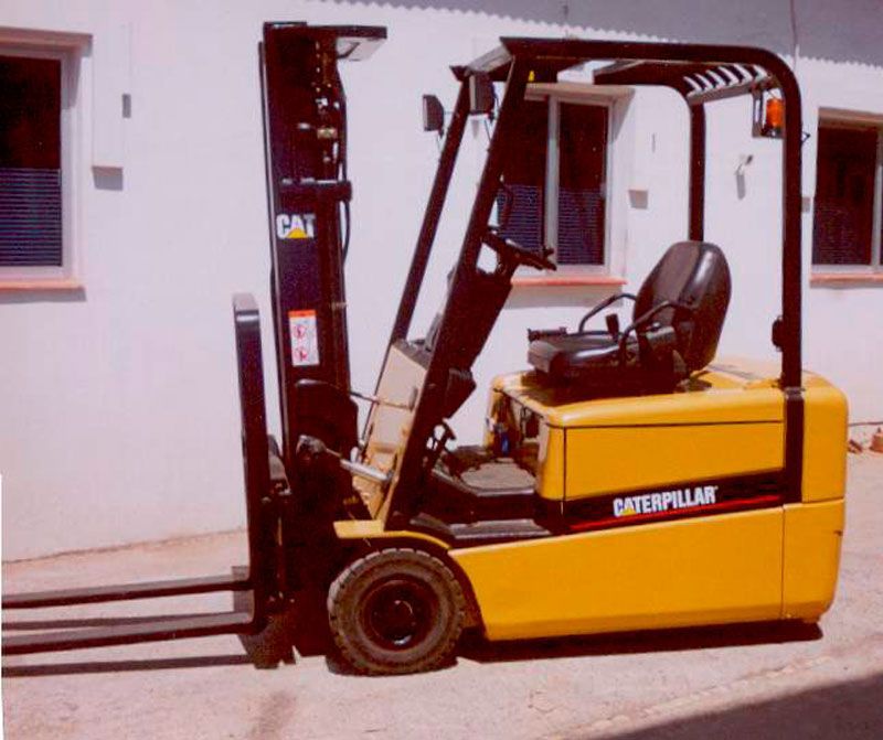 Una carretilla elevadora Caterpillar amarilla está estacionada frente a un edificio blanco
