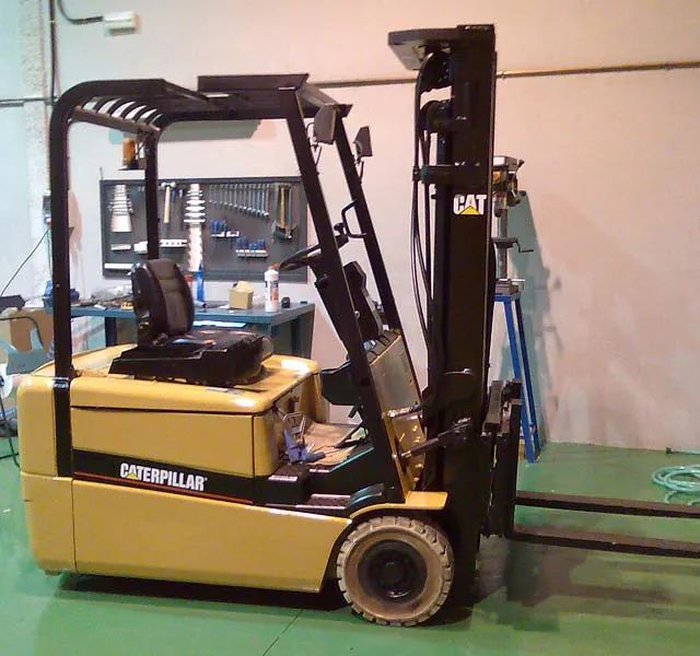 Una carretilla elevadora Caterpillar está estacionada en un piso verde