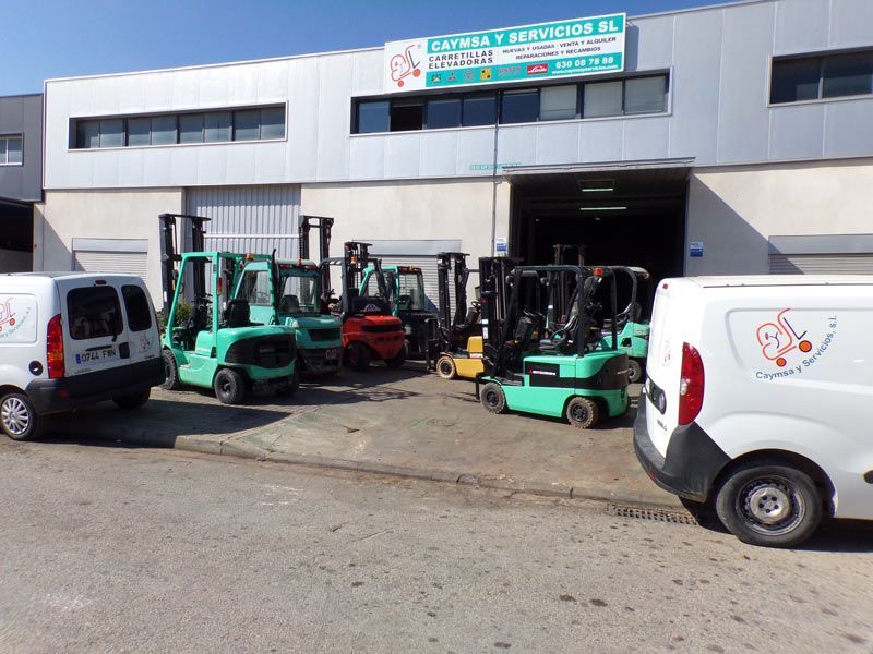 Un montón de carretillas elevadoras están estacionadas frente a un edificio.