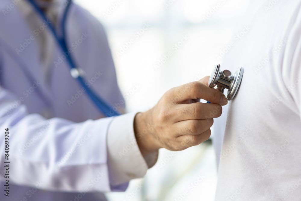 Der Arzt zeigt mit einem roten Stift auf einen EKG-Ausdruck; das Stethoskop ist sichtbar.