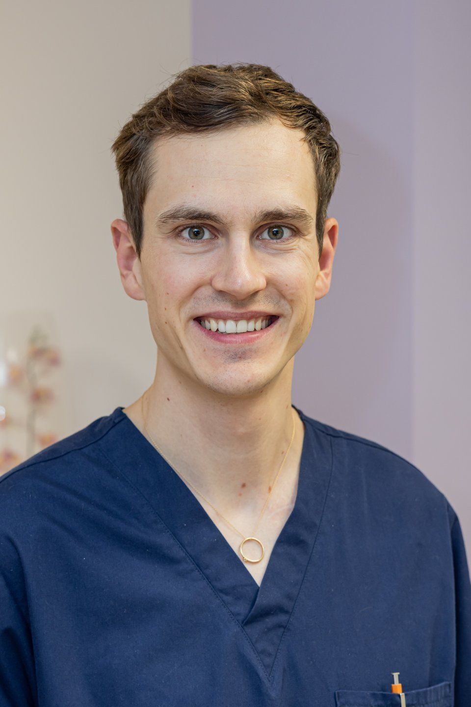 Frau mit langen, leuchtend roten Haaren lächelt in einem rosa Hemd in einem Büro.